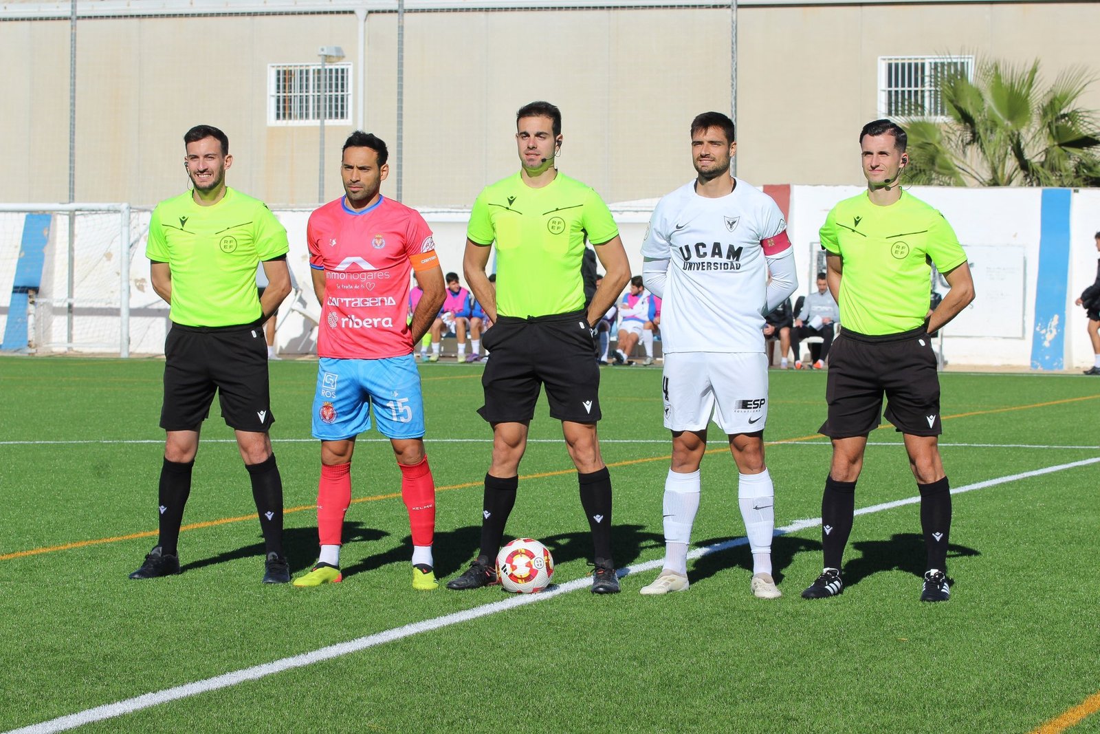 Foto protocolaria con los 2 capitanes, el árbitro y los 2 linieres como protagonistas. Fuente: UCAM Murcia CF "X"