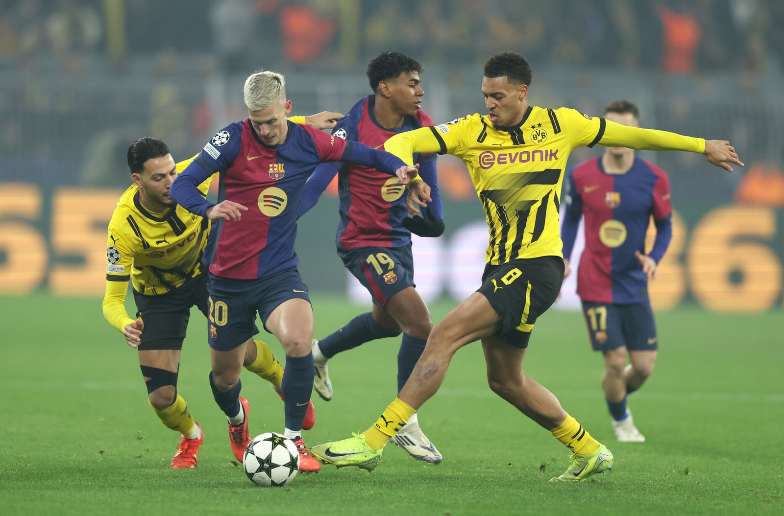 DORTMUND, GERMANY - DECEMBER 11: Dani Olmo of FC Barcelona is challenged by Ramy Bensebaini and Felix Nmecha of Borussia Dortmund during the UEFA Champions League 2024/25 League Phase MD6 match between Borussia Dortmund and FC Barcelona at BVB Stadion Dortmund on December 11, 2024 in Dortmund, Germany. (Photo by Lars Baron/Getty Images)