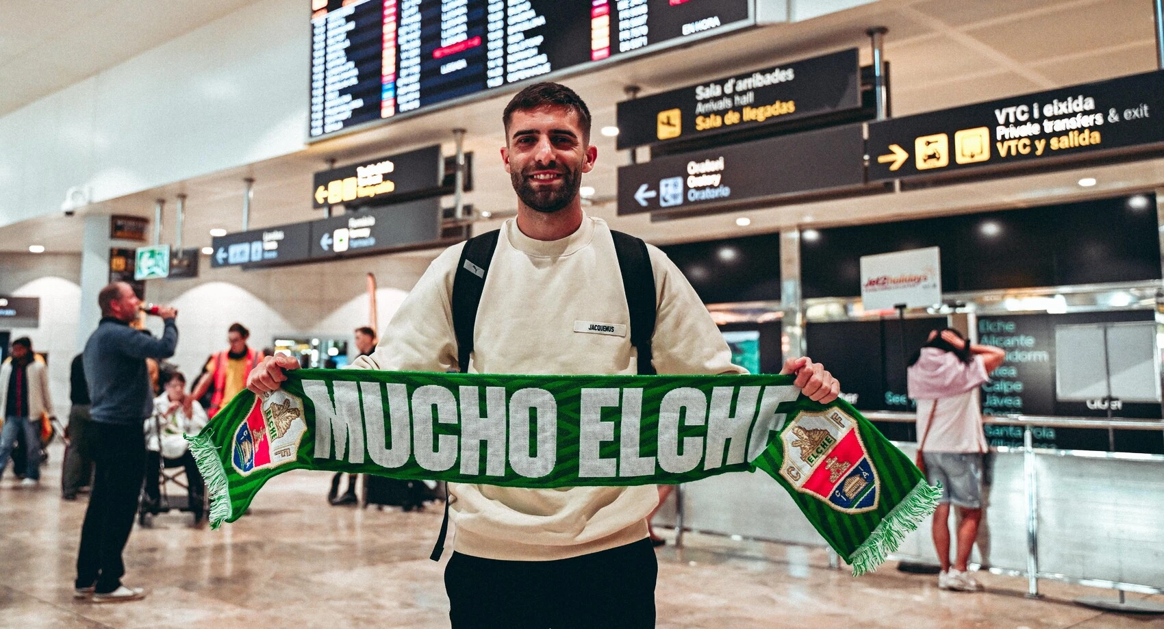 Pejiño posa con una bufanda del Elche en su llegada al aeropuerto. Foto: Elche CF.