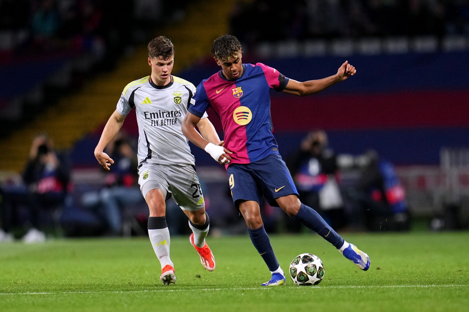 BARCELONA, SPAIN - MARCH 11: Lamine Yamal of FC Barcelona runs with the ball under pressure from Samuel Dahl of SL Benfica during the UEFA Champions League 2024/25 UEFA Champions League 2024/25 Round of 16 Second Leg match between FC Barcelona and SL Benfica at Estadi Olímpic Lluís Companys on March 11, 2025 in Barcelona, Spain. (Photo by Aitor Alcalde/Getty Images)