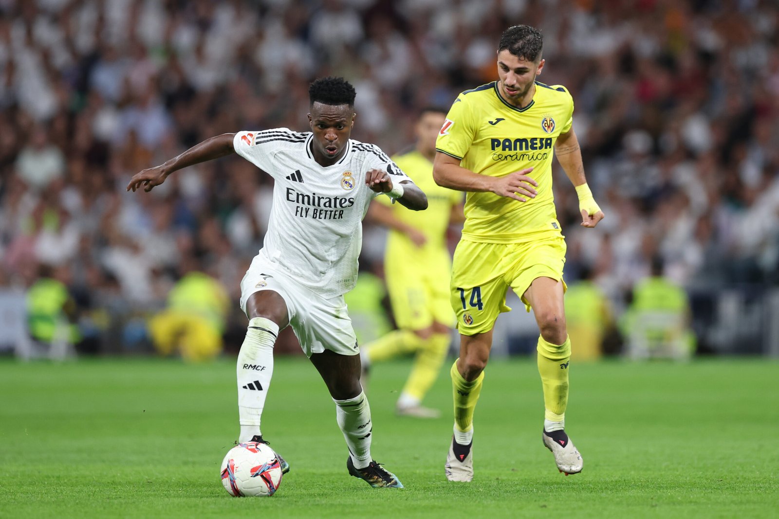 Vinicius Junior (izq.) del Real Madrid CF disputa el balón con Santiago Comesaña (der.) del Villarreal CF durante el partido de LaLiga entre el Real Madrid CF y el Villarreal CF en el Estadio Santiago Bernabéu el 5 de octubre de 2024 en Madrid, España.